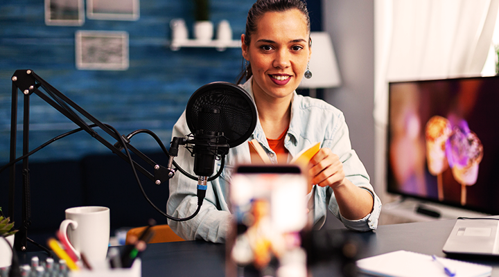 Photo of a woma on her desk in front of a mic